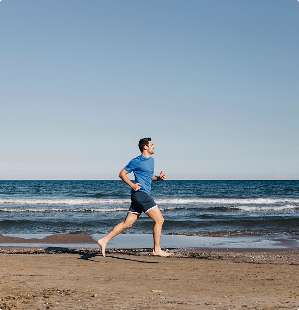 A man jogging along the shoreline, with waves gently lapping at the sand under a clear blue sky. A man jogging along the shoreline, with waves gently lapping at the sand under a clear blue sky.
