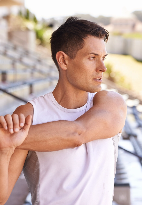 A man stretches his arm on a tennis court, preparing for a serve or rally during a match. A man stretches his arm on a tennis court, preparing for a serve or rally during a match.