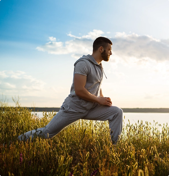A man in a gray suit practices yoga on green grass, demonstrating a pose with focus and balance. A man in a gray suit practices yoga on green grass, demonstrating a pose with focus and balance.