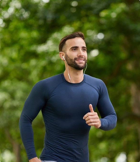 A man runs in the park wearing earbuds, enjoying music while exercising outdoors. A man runs in the park wearing earbuds, enjoying music while exercising outdoors.