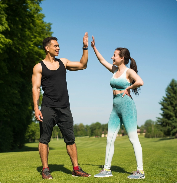 A man and woman smiling as they give each other a high five in a celebratory gesture. A man and woman smiling as they give each other a high five in a celebratory gesture.
