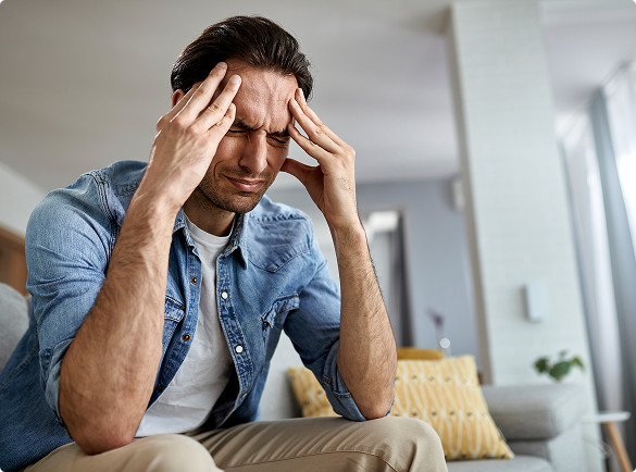 A man on a couch, hands on his head, conveying a sense of contemplation or frustration. A man on a couch, hands on his head, conveying a sense of contemplation or frustration.
