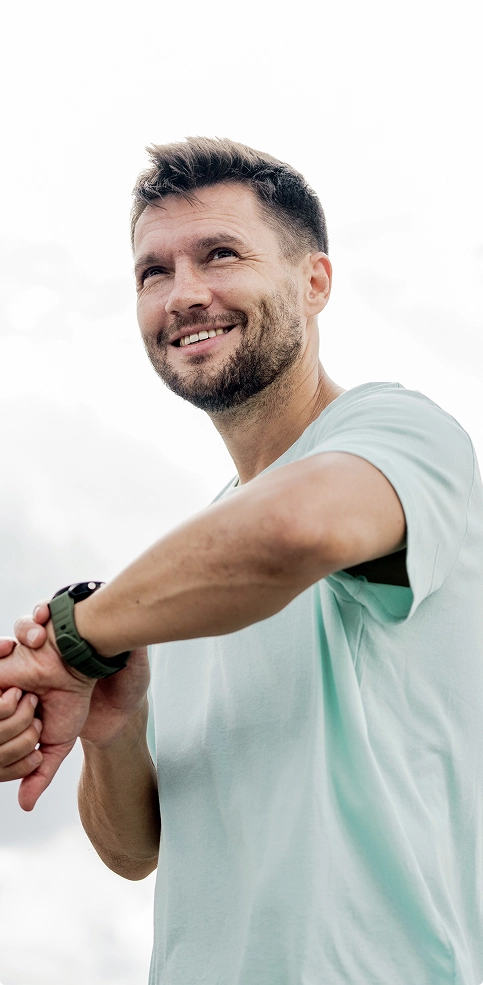 A smiling man holds his wristwatch, showcasing its design and his joyful expression. A smiling man holds his wristwatch, showcasing its design and his joyful expression.