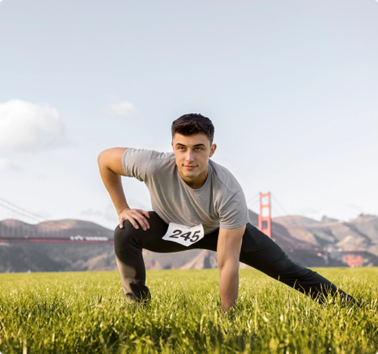 Rectangle 3214 A man in a field gazes at the Golden Gate Bridge, framed by lush greenery and a bright sky.