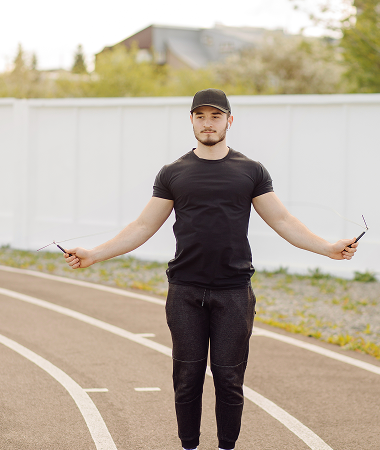 A man stands on a running track, arms outstretched, as if celebrating or welcoming an event. A man stands on a running track, arms outstretched, as if celebrating or welcoming an event.
