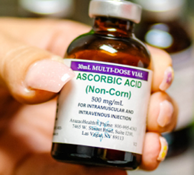 A person holding a bottle of ascorbic acid, showcasing the label and the clear liquid inside the bottle.