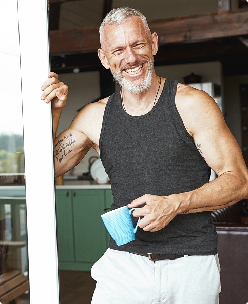 an old man smiling with hold a coffee cup in hand