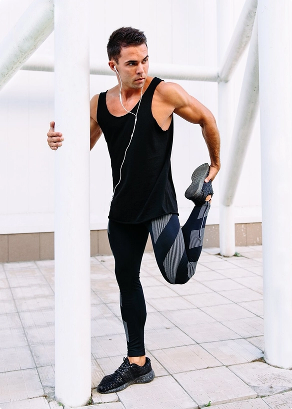A man in a black tank top and leggings stretches his body, focusing on flexibility and fitness A man in a black tank top and leggings stretches his body, focusing on flexibility and fitness