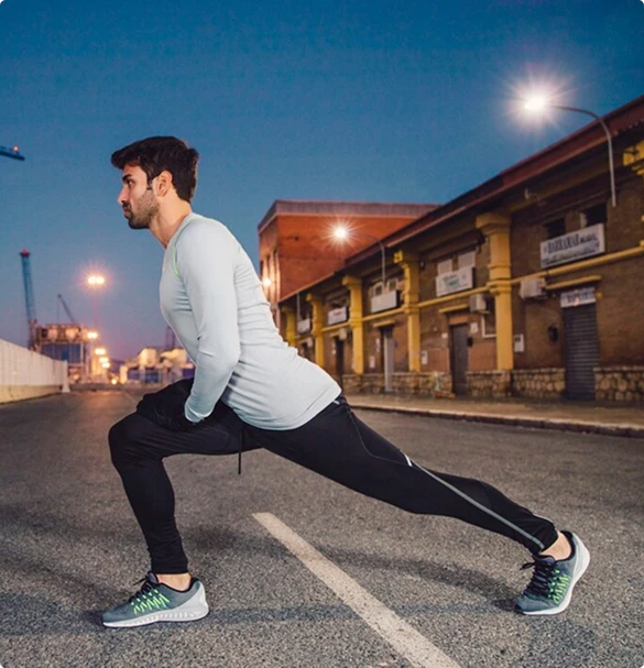 A man performs a stretching exercise on the road, showcasing his fitness routine in a public space.