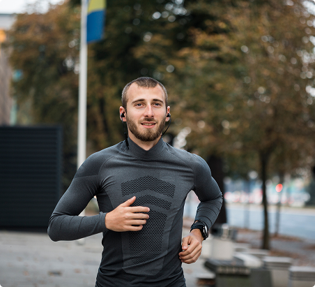 A man jogging on a city street, wearing athletic gear and focused on his run. A man jogging on a city street, wearing athletic gear and focused on his run.