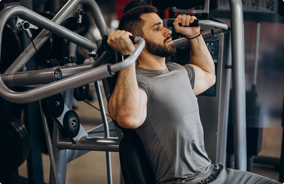 A man performs a chest press exercise on a bench in a gym, focusing on strength training.