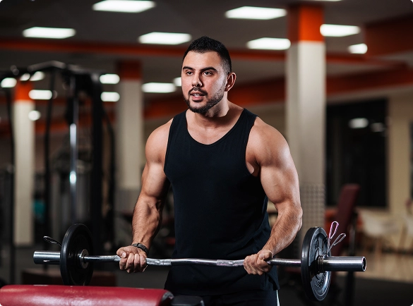 A man is lifting a barbell while exercising in a gym, focusing on strength training.
