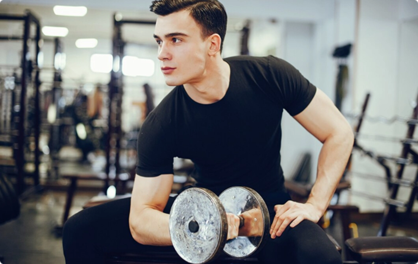 A man is lifting a dumbbell while exercising in a gym setting.