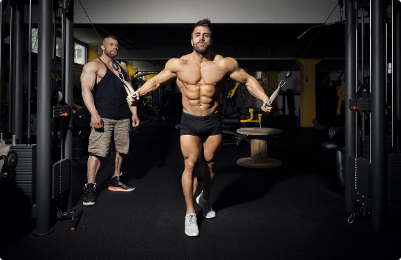A man stands in front of a gym machine, to use it for his workout routine.