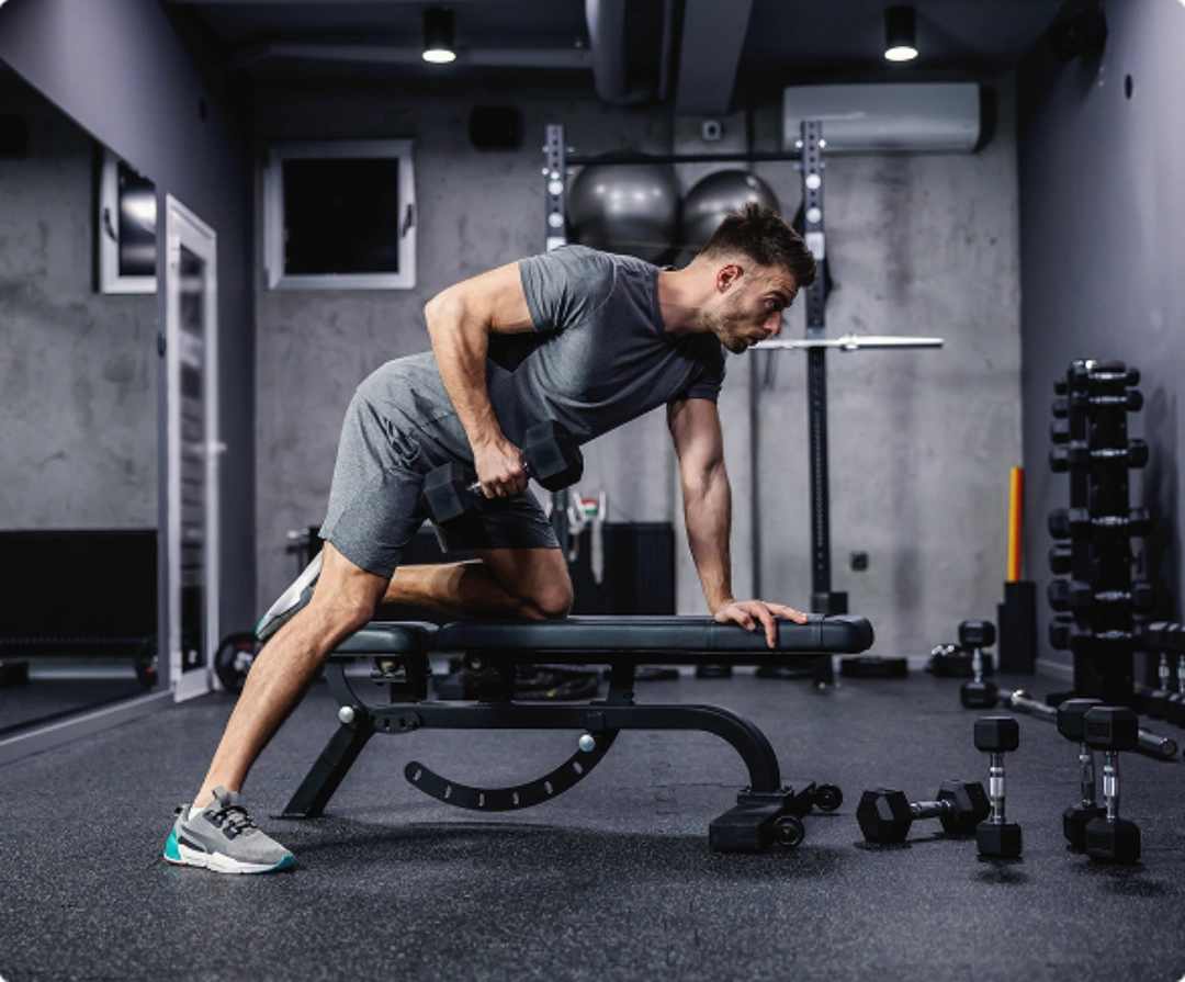 A man performs a dumbbell exercise in a gym, focusing on strength training and fitness.