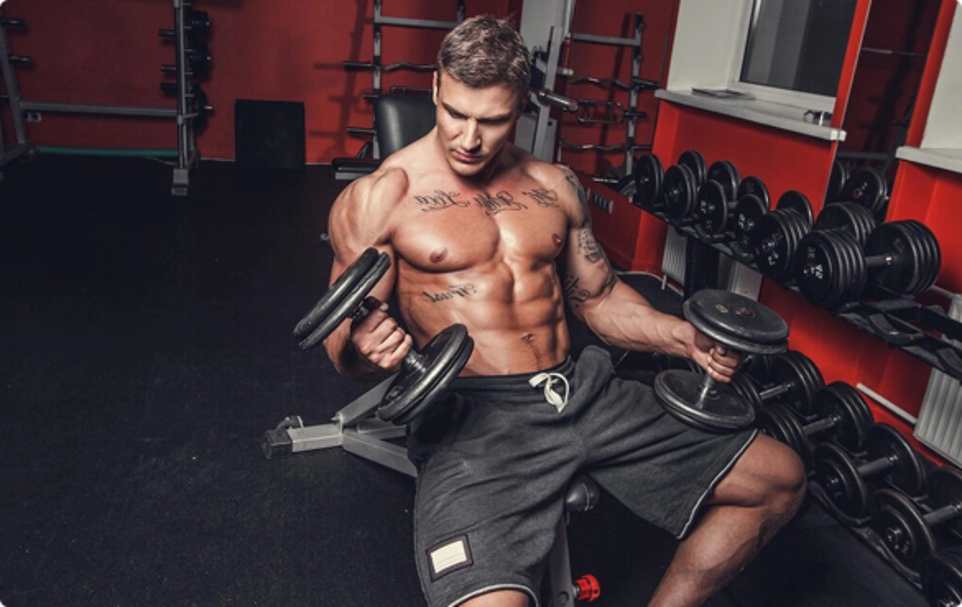 A man performs strength training with dumbbells in a gym, showcasing his workout routine.
