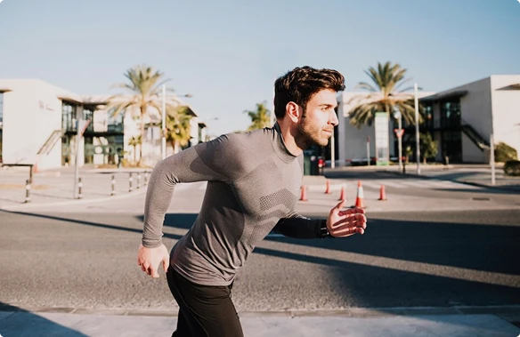 A man jogs on a road, showcasing determination and fitness in his running attire.