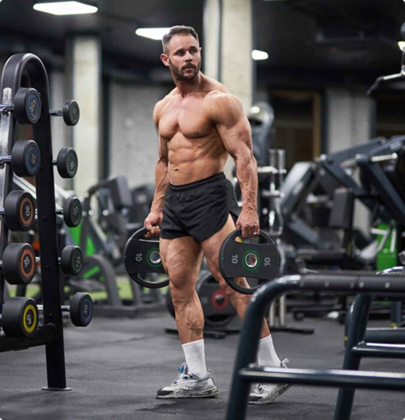 A boy lifting round weight plates in a gym during a strength workout.